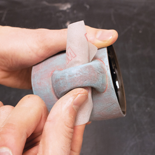 2 Sanding the surfaces of a fired mug to soften edges and enhance tactile appeal.