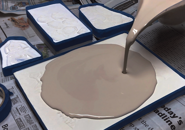 F Tape around the perimeter of the bone-dry plaster carvings; pour porcelain slip from the center out and until it reaches about 1/4 inch (0.5 cm) thick or a little thicker. Wait until the porcelain loses its shine before smoothing with a rib, then when it is solid, remove from the plaster. 