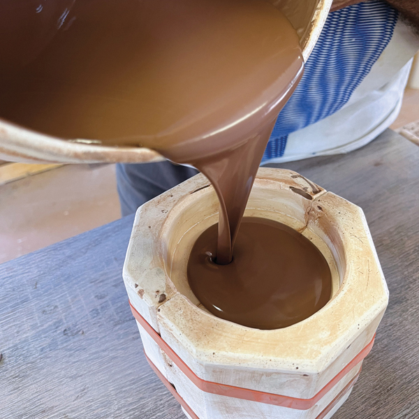 1 Pour a red-earthenware casting slip into a dry plaster mold to create a small oval-shaped cup.