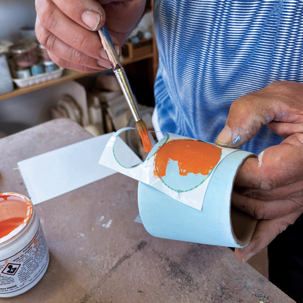 7 Use a stencil to apply the final layer of orange underglaze.