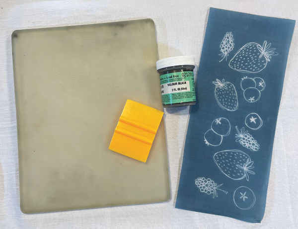 1 Materials for printing from left to right: 8×10 in. Gelli plate, yellow squeegee, Amaco Velvet Velour Black underglaze, silkscreen with hand-drawn berry illustration. 