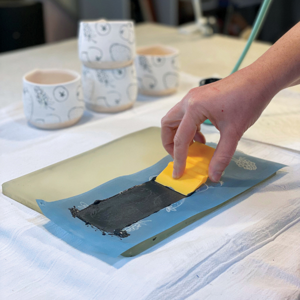 3 Use the squeegee to spread the underglaze over the image, making sure to apply the color evenly. 