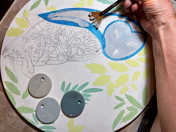 7 Block in main color areas using a fan brush and paper or vinyl stencils to quickly lay down three coats of underglaze.