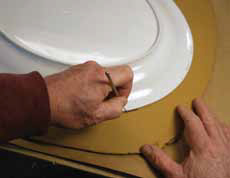 2 Place the platter form upside down on the slab and use a needle tool to cut out the shape from the slab.