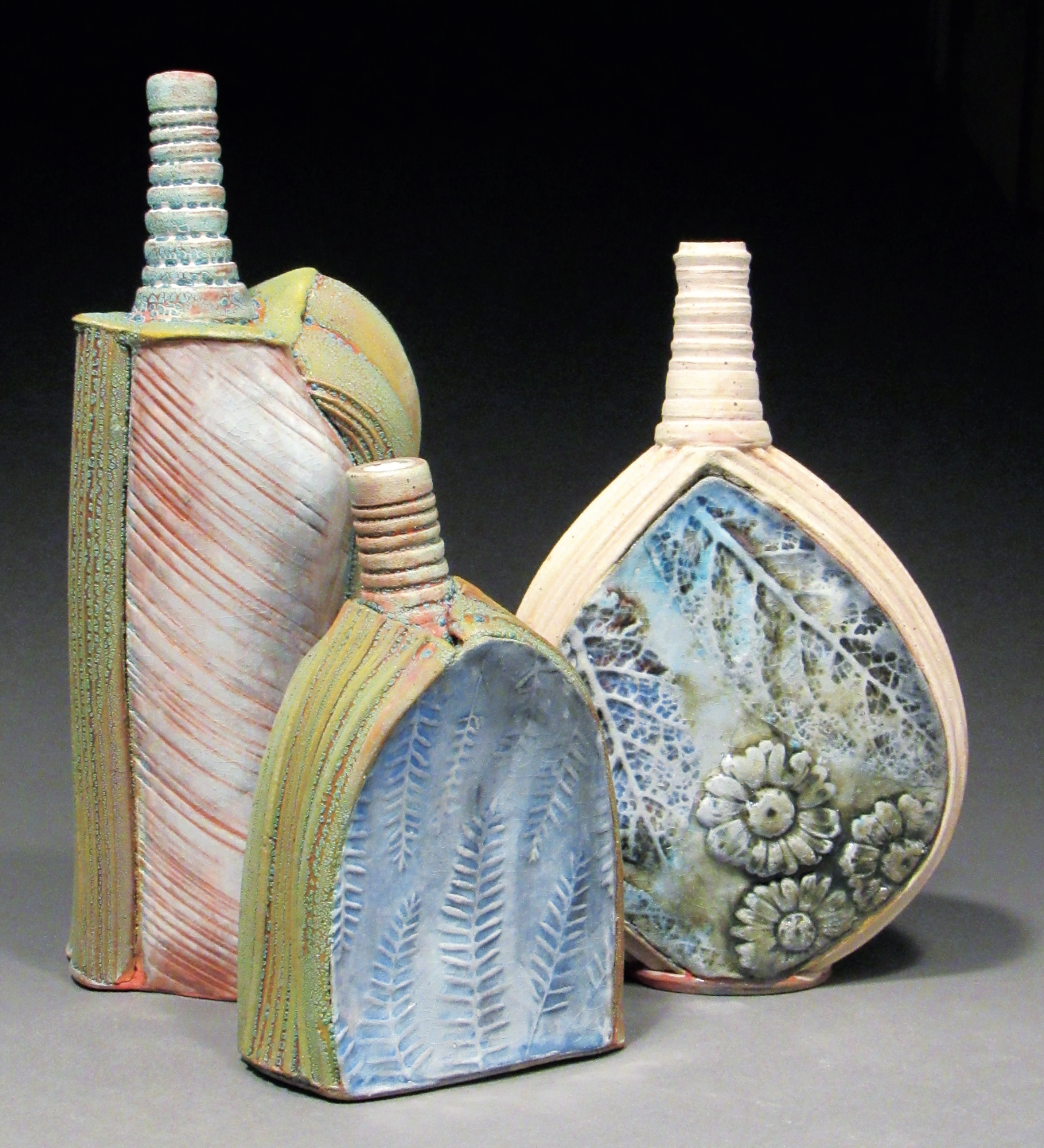 David Scott Smith’s bottles, wheel-thrown, extruded, and press-molded clay components, decorated with underglaze washes and low-fire glazes, and fired in a low-fire wood kiln (converted from an electric kiln) to cone 1.