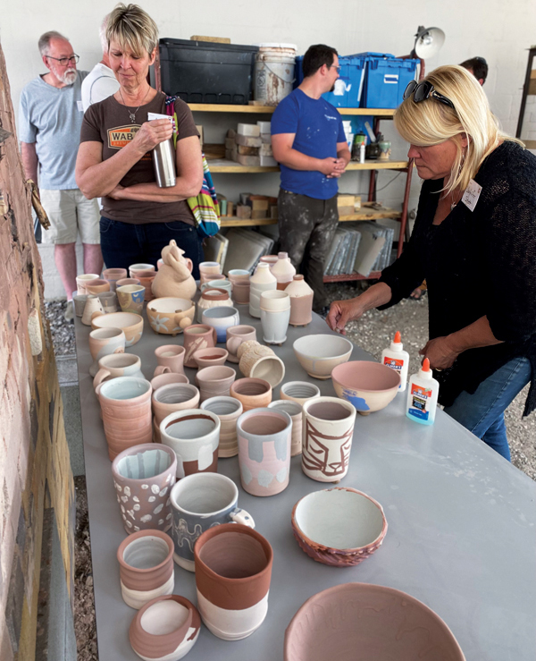 2 Participants glazing, decorating, and wadding their work for the preconference soda firing. 