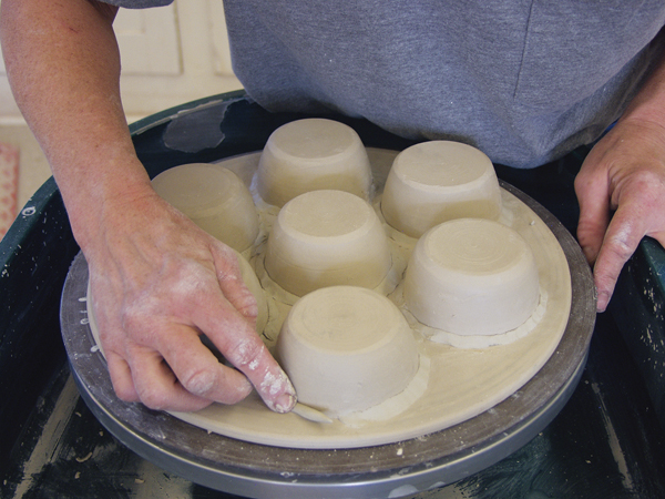 5 Brush slip or magic water around the rim of each cup and push it into the hole. Smooth a thin coil around each cup.