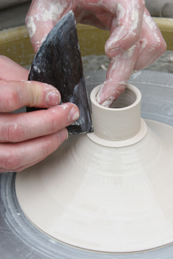 8 Throw the top portion of the flask and pull the wall inward into a volcano shape. Use the right angle of a wooden rib to push in a lid seat at the top of the form.