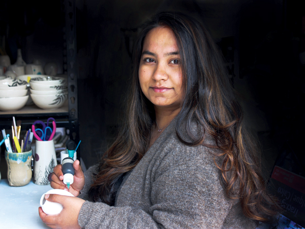 Yesha Panchal In her studio, decorating pottery. 
