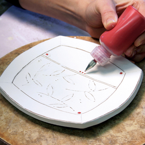 7 Add accent colors by applying underglaze using a slip trailer, then bisque fire the plate.