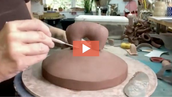 Image of Jen Allen fine tuning a clay handle on a jar lid.