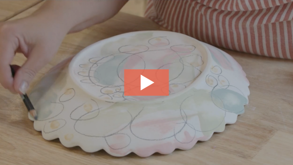 Image of Angelique Tassistro decorating a bisque plate using an underglaze pencil
