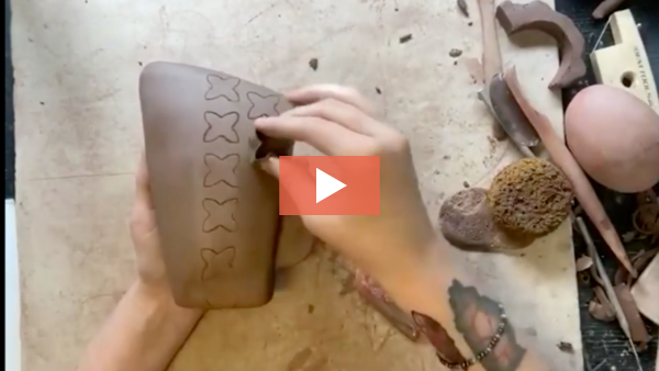 Image of Taylor Mezo stamping a design into a slab-built vase.