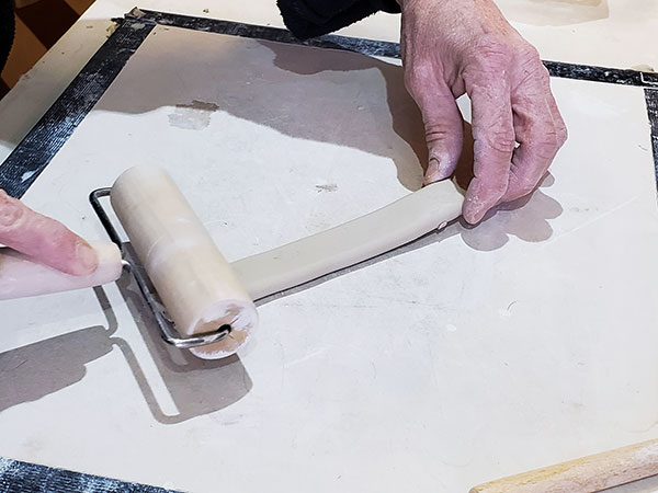 3 Hold the oval segment at one end, then use a pony roller to thin and stretch the clay, rolling from the free end toward your hand.