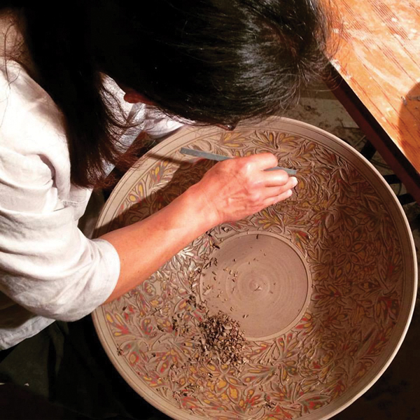 3 Kim Seong-Tae carving through layers of colored slip on the surface of a large platter.