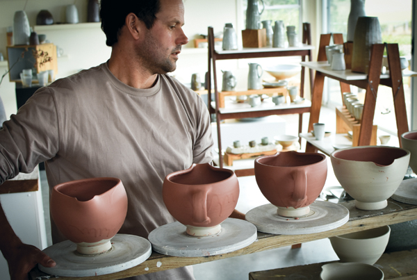 1 Zak Chalmers carries a ware board of raw glazed mixing bowls through the gallery on the way to placing them outside to dry.