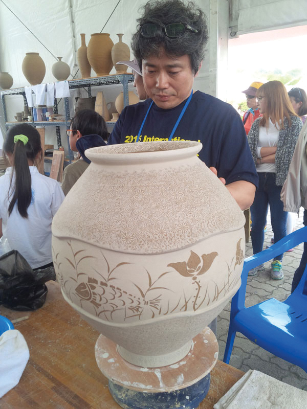 9 You Yong-Chul carving through white slip and adding stamped decoration to a large vessel.