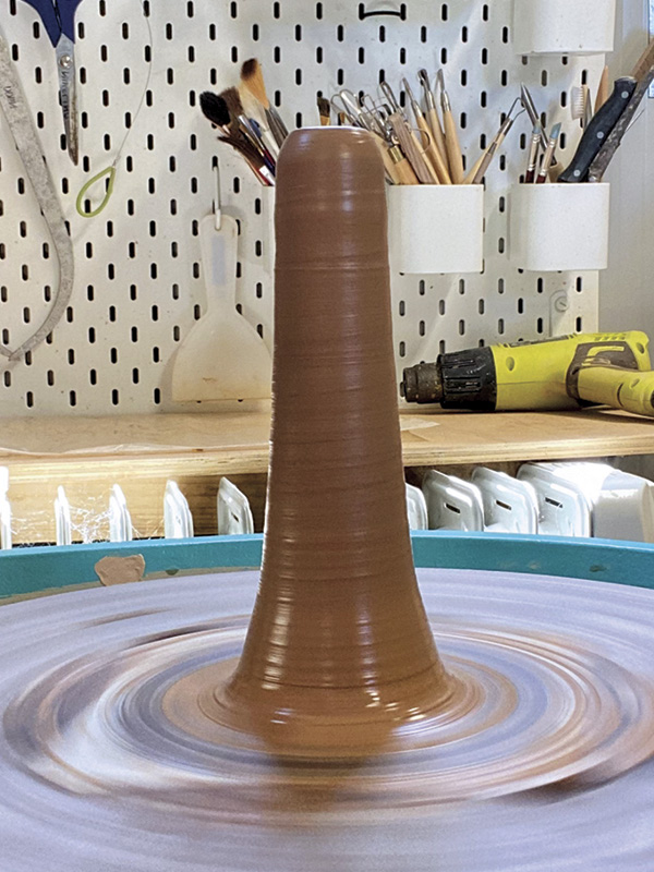 1 Cone the clay on the wheel to the desired height (at least a couple of inches taller than the depth of your pot) while making the base narrower than the pot opening.
