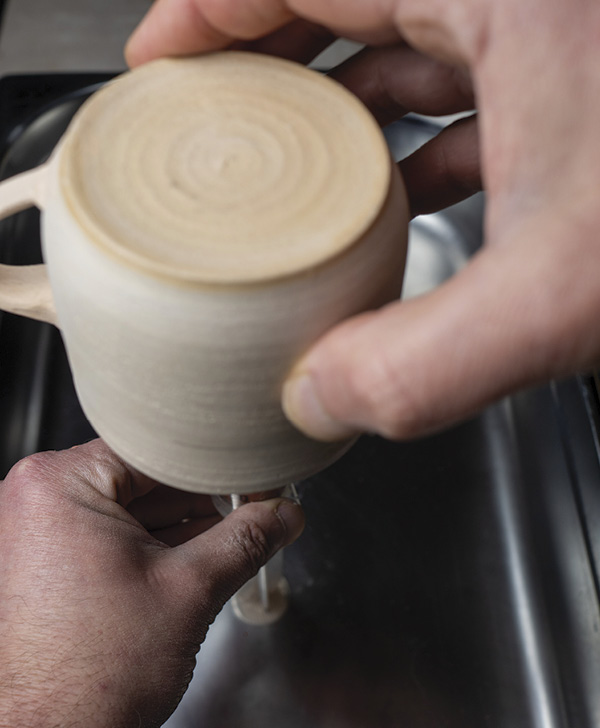 3 Hold the pot over the syringe and push down the plunger with the other hand so the glaze sprays onto the inside of your pot (and covers your hand in glaze).