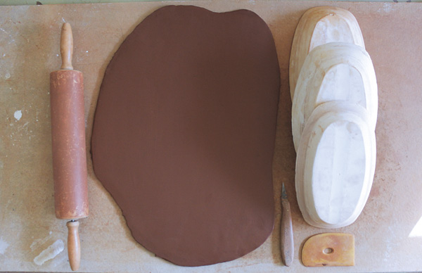 4 Roll out a slab of clay and cut shapes slightly larger than the footprint of your mold.