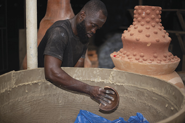 4 Okai building with clay slabs, shaping the form with a broken ceramic pot. Photo: Roy Okai Boateng.