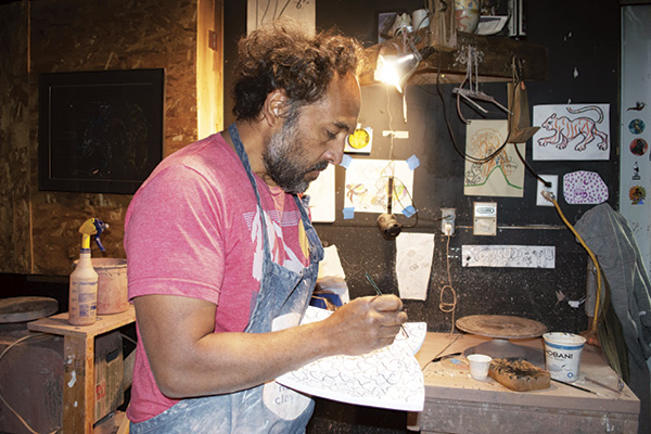 1 Peter Jadoonath painting a plate in his pottery studio.