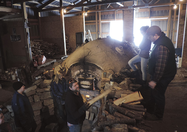 Samuel Johnson firing the anagama-type kiln with students. Photo: Mitch Iberg and Zoe Powell.