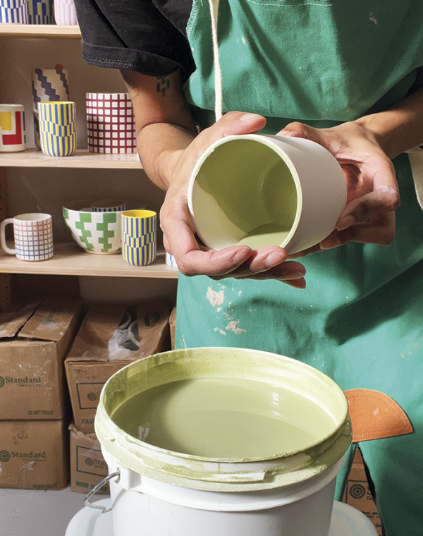 1 Fill your pot with glaze, then bring your dominant hand to the rim, your non-dominant hand to the back of your piece, tilt downward, and spin 360°.