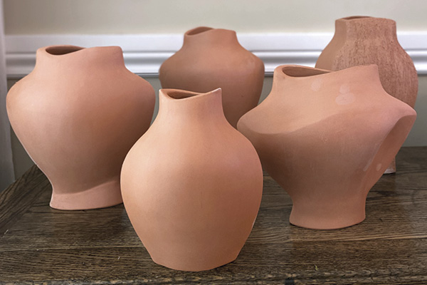 9 Bisque-fired vases made using cardboard slump molds.