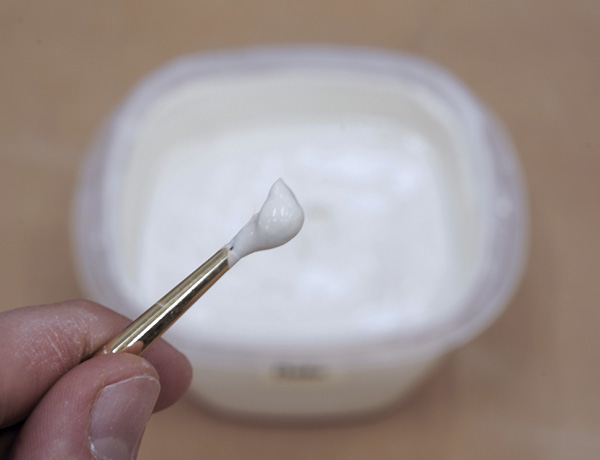 8 Dip a paintbrush in the slip and apply it onto a dry stick of clay.