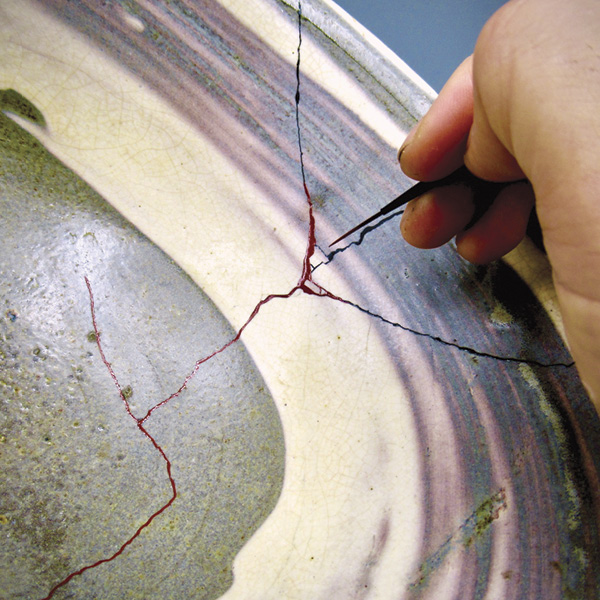 4 Fukumaru in her studio in 2021 applying a layer of urushi lacquer with a maki-e brush to the joins of a bowl with hakeme decoration by Rosanjin (1883–1959).