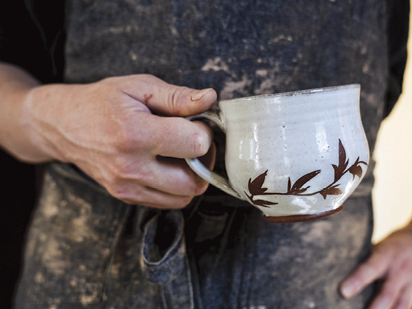 Hand holding finished mug by Kyla Strid.