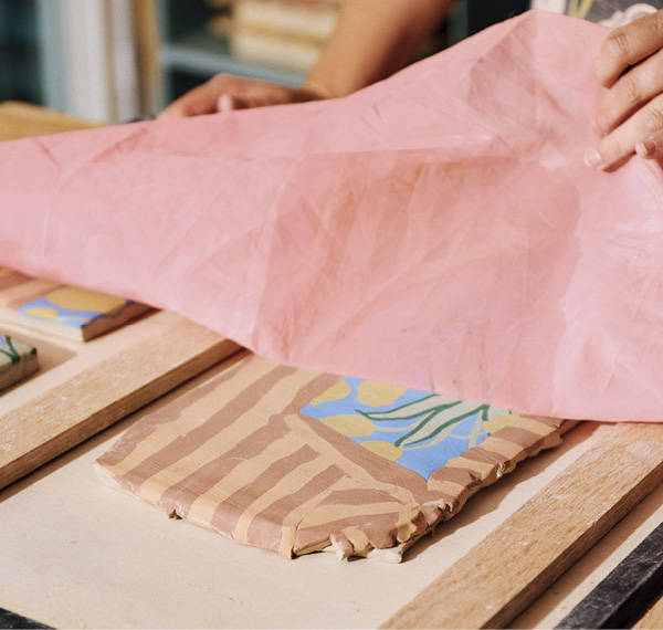 5 Peeling back the fabric after using a rolling pin to connect the collaged components together.