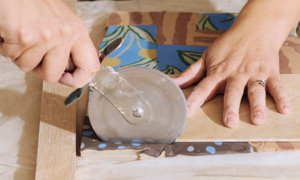6 Poag using a pizza cutter to remove excess material using a template as a guide.