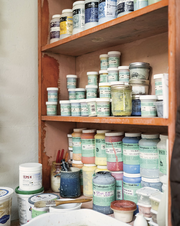 A shelf in Marney McDiarmid'd studio, holding many jars of glaze.