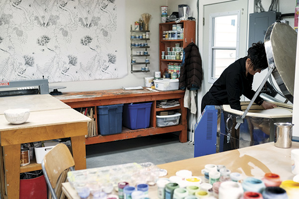 A view of Marney McDiarmid's studio, showing her at her open kiln.