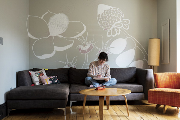 Marney McDiarmid sitting cross-legged on a couch, sketching in a notebook.