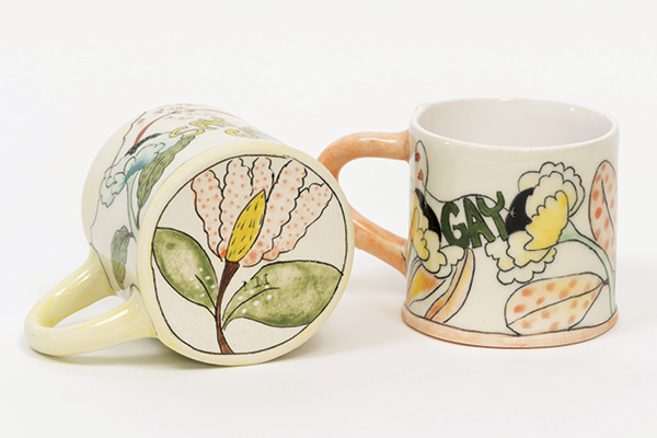 Marney McDiarmid's two finished mugs, one laying on its side to show the decoration on the bottom.