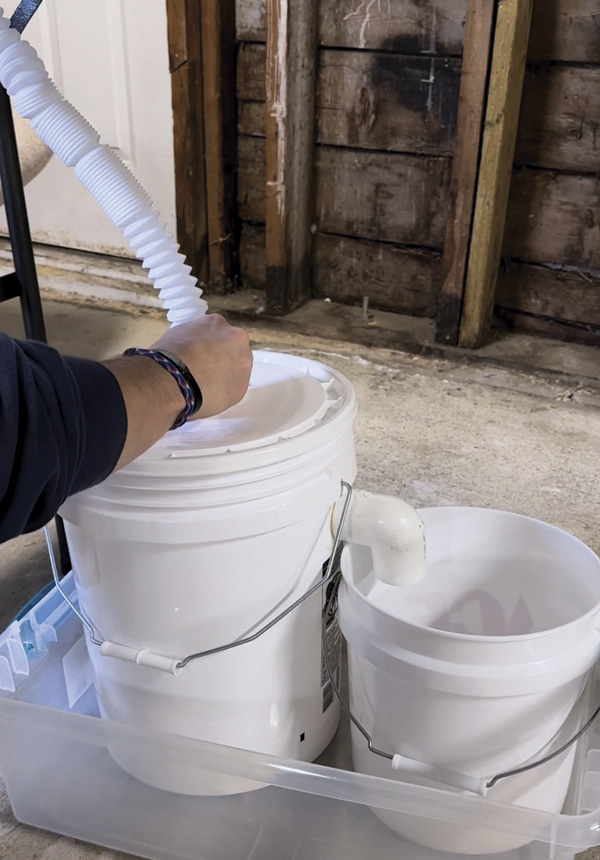 3 Using the camping sink’s adjustable drain pipe, connect the sink to the larger bucket.