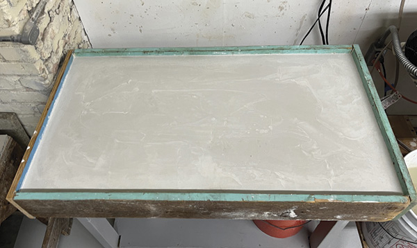 5 The poured and smoothed plaster, beginning to harden and cure within the table frame.