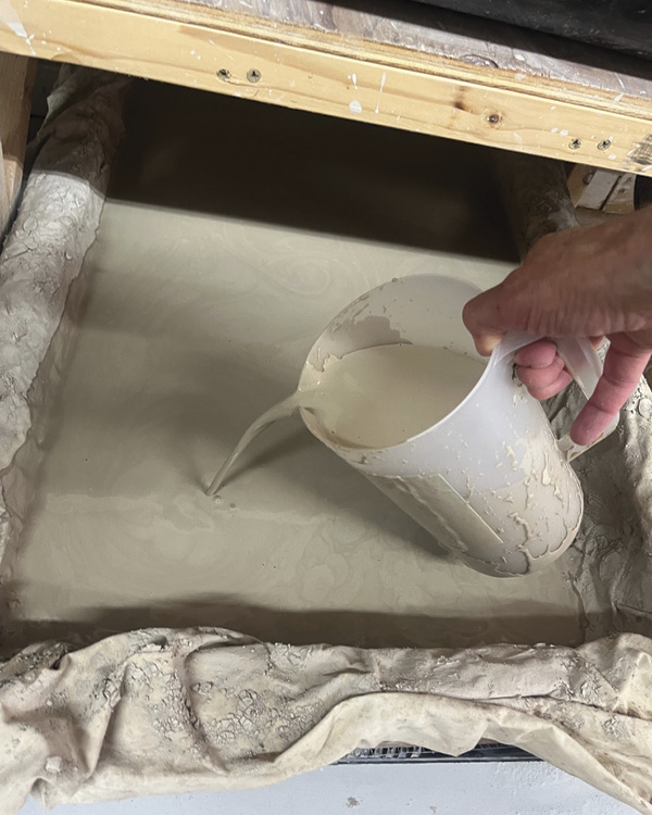 7 Pouring the smooth, mixed slip reclaim into the wooden frame with ¼-inch hardware cloth and lined with two muslin sheets.
