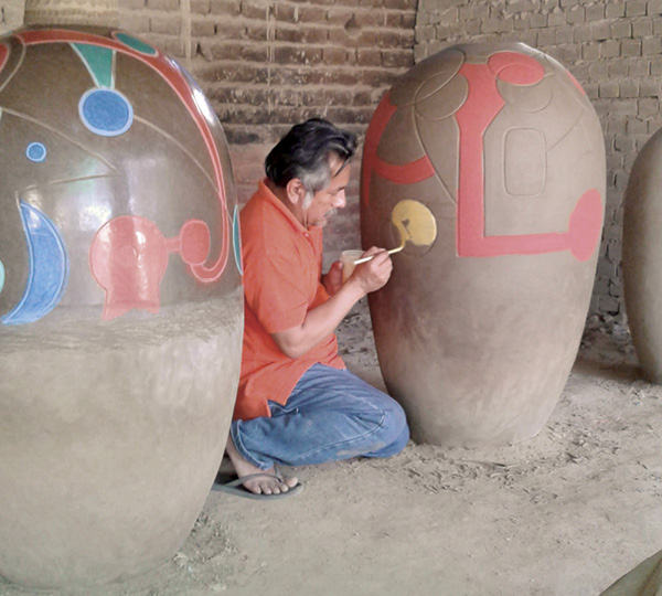 3 Ramírez applying engobes to a vessel, to be fired in an adobe kiln at 1650°F (899°C), for the project “Chulucanas Monumental,” in Chulucanas, Peru, 2015.