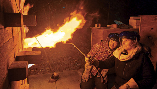 1 Tracy Gordon (and assistant) introducing soda ash into her kiln at cone 8 during a firing.
