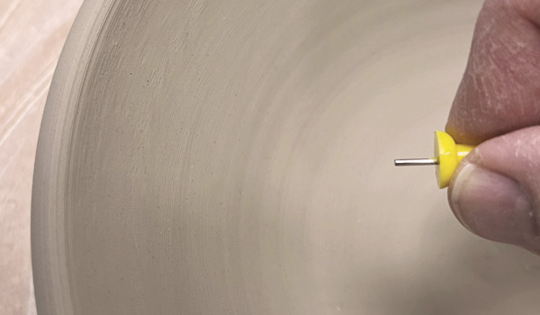 1 Using a bowl as an example, take a thumbtack and clip the pointy end shorter with pliers or scissors so the remaining shaft matches your desired wall thickness.