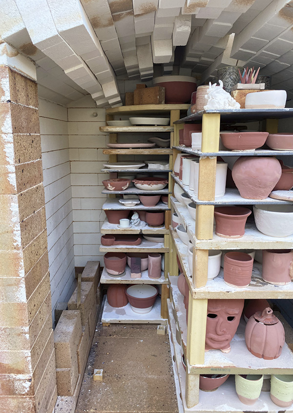 2 The front left stack of shelves cleared, allowing access to the back of the kiln, showing the wedged arch bricks.