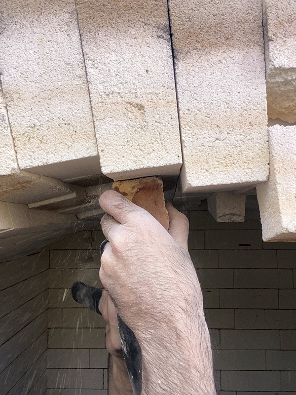 3 Use a soft brick to gently tap the arch back into place; the soft brick helps minimize damage to the arch bricks from the resetting process.
