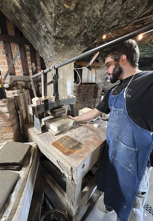 17 Eric Moore operates the tile press in the production studio. Photo: Andrew Buck.