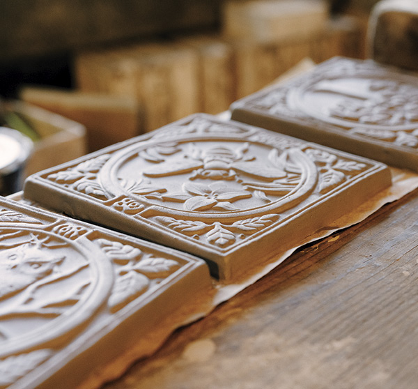 18 Unfired seasonal special edition contemporary Summer tiles lined up on a worktable in the production studio. Photo: The Tileworks of Bucks County.