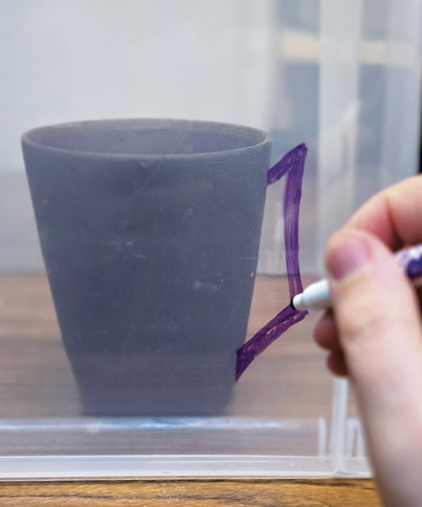 1 Using a dry-erase marker, draw onto the clear bin, sketching out ideas such as handles.