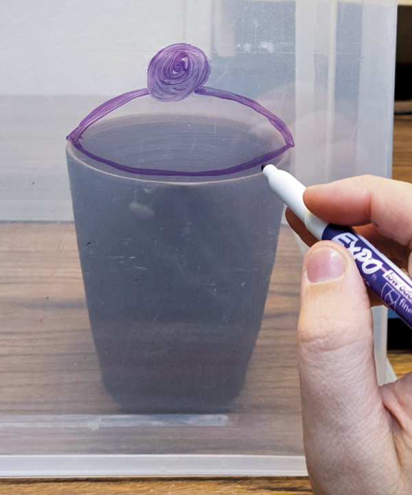 3 Using a dry-erase marker, draw onto the clear bin, sketching out ideas such as lids.